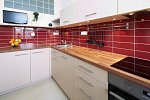 Celkový pohled na červenobílou moderní kuchyni v bytě na Vinohradech